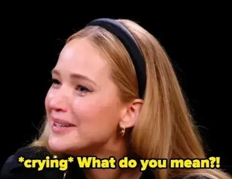 The Jennifer Lawrence reaction meme: she looks up with tears in her eyes against a black background, under a yellow caption reading "*crying* What do you mean?!".